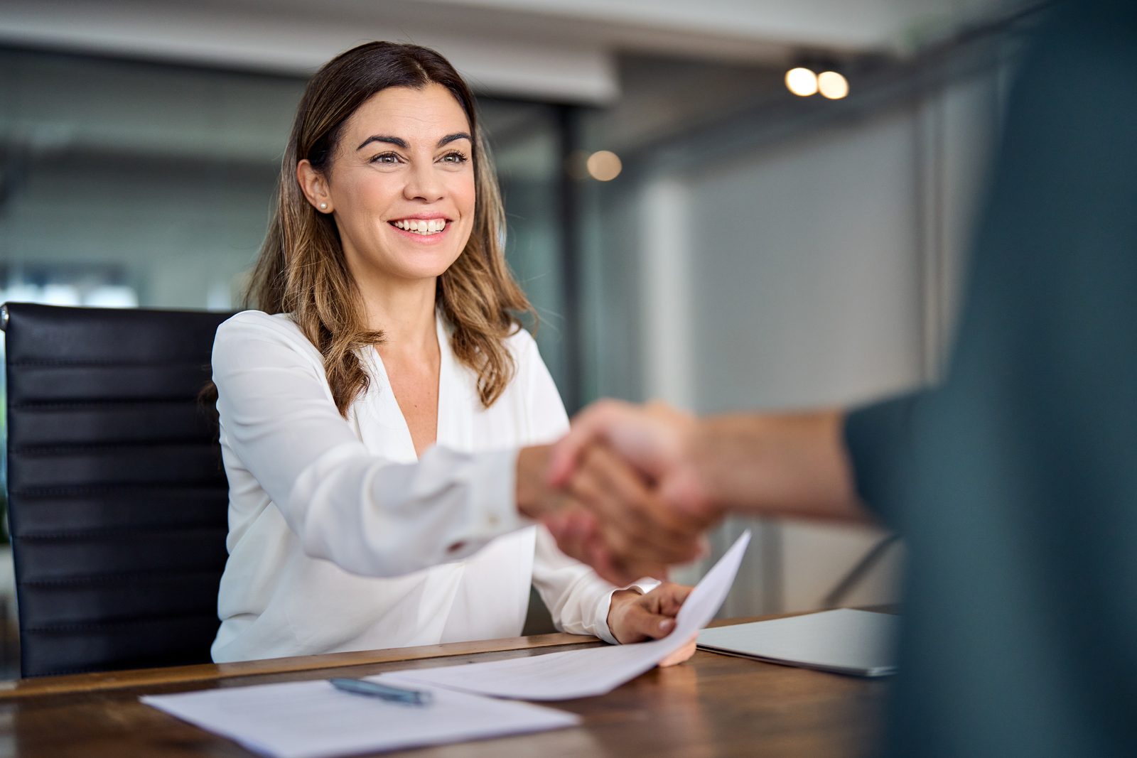 M1 Solutions advisor shaking hands with a business owner across a desk